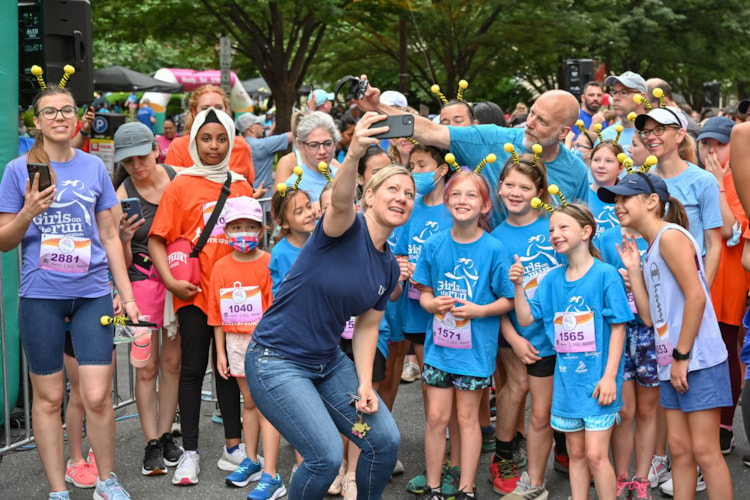 Kristen Cheman taking a selfie with Girls on the Run participants before the Spring 2022 5K at Ballston.